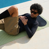 Mini tapis de sol pad de confort de la marque hercule studio modèle galé couleur outrenoir posé sur le tapis d'exercice archy couleur pistache avec mannequin allongé dessus