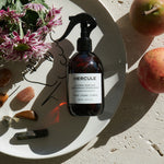 Spray pour assainir le tapis de sport et énergiser l'espace d'entraînement photo du produit sur une assiette et disposition de fleurs et pierres 