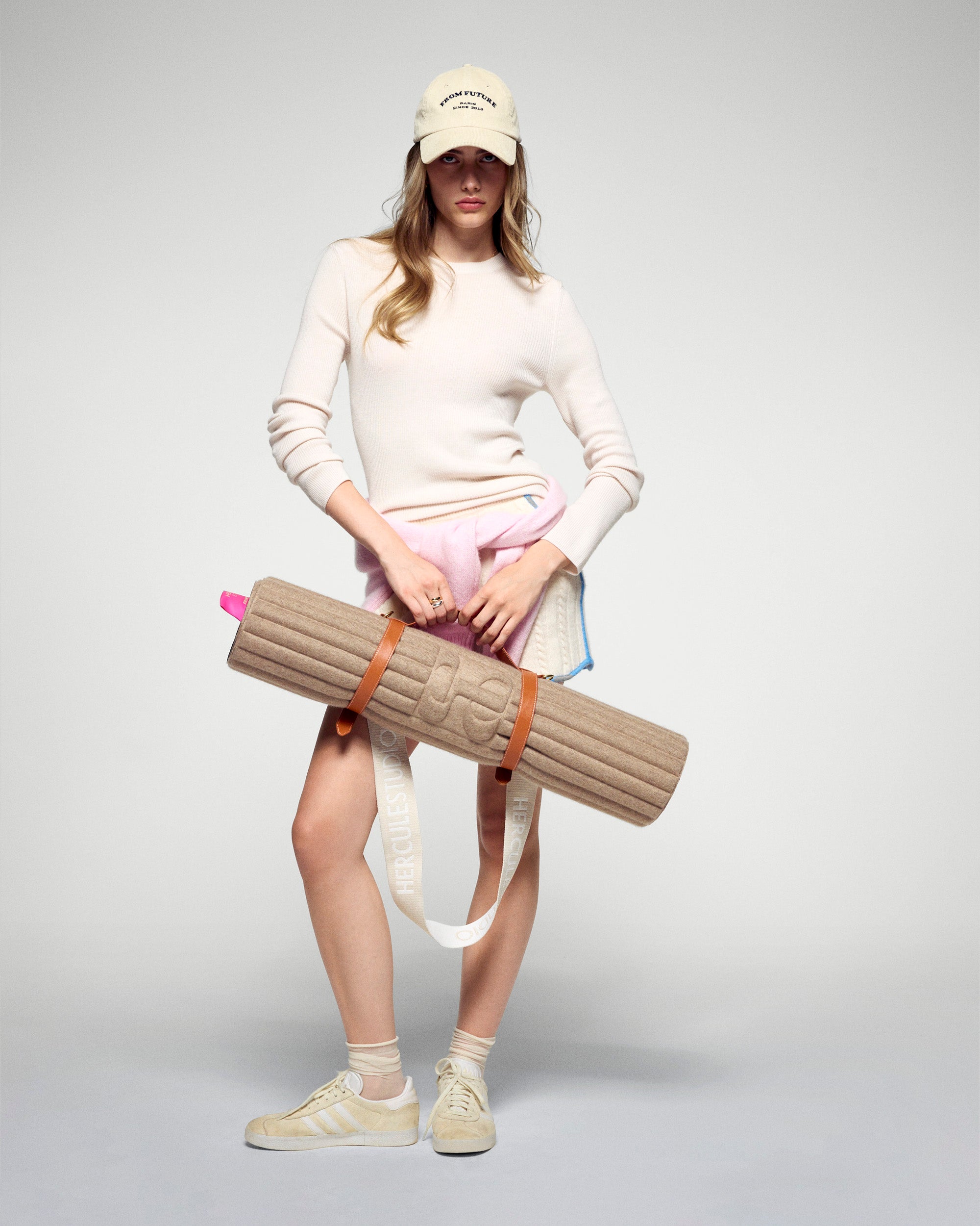 Tapis de sol pour le fitness le yoga et le pilates en cachemire de la marque hercule studio en collaboration édition limitée avec from future modèle archy couleur beige photo lifestyle avec mannequin et sangle de transport soca