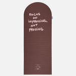 Hercule Studio x Thomas Lélu Limited Edition Exercise Mat, brown designer floor mat featuring a pink quote reading “focus on improving not proving,” an artistic collaboration for fitness, Pilates, and stretching, unfolded view