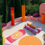 Tapis de sol pour le fitness le yoga et le pilates de la marque hercule studio en collaboration avec uchronia modèle archy imprimé summer shooting déplié sur un fond architectural et estivale réalisé par l'inteligence artificielle