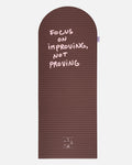 Hercule Studio x Thomas Lélu Limited Edition Exercise Mat, brown designer floor mat featuring a pink quote reading “focus on improving not proving,” an artistic collaboration for fitness, Pilates, and stretching, unfolded view