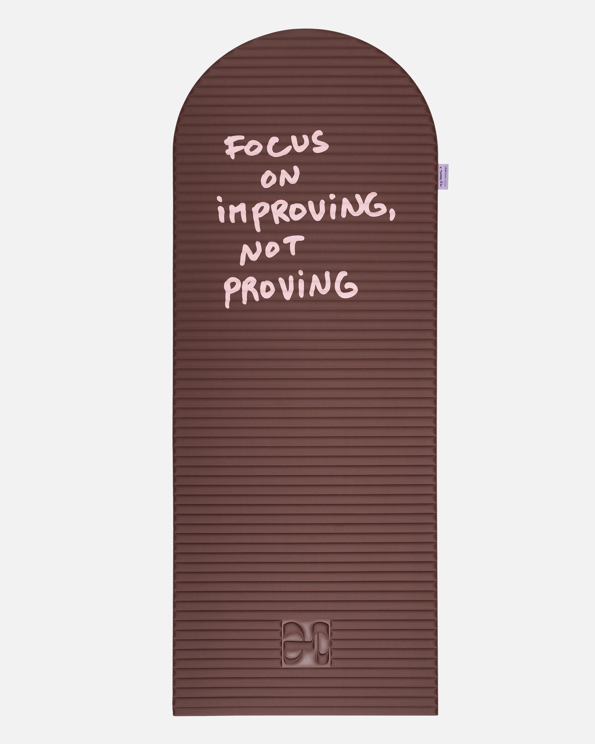 Hercule Studio x Thomas Lélu Limited Edition Exercise Mat, brown designer floor mat featuring a pink quote reading “focus on improving not proving,” an artistic collaboration for fitness, Pilates, and stretching, unfolded view