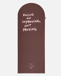 Hercule Studio x Thomas Lélu Limited Edition Exercise Mat, brown designer floor mat featuring a pink quote reading “focus on improving not proving,” an artistic collaboration for fitness, Pilates, and stretching, unfolded view