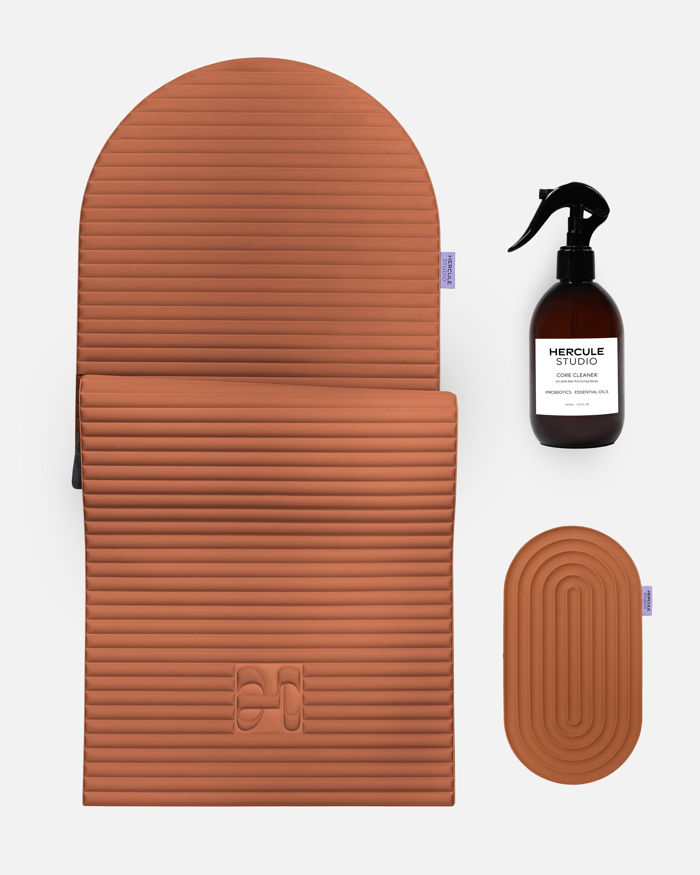 Hercule Studio terracotta essential bundle including the Archy arch-shaped sport mat, the Galé 3-in-1 comfort pad for knees and elbows and the sanitizing spray, durable Made in France Pilates and fitness bundle, packshot of grouped products